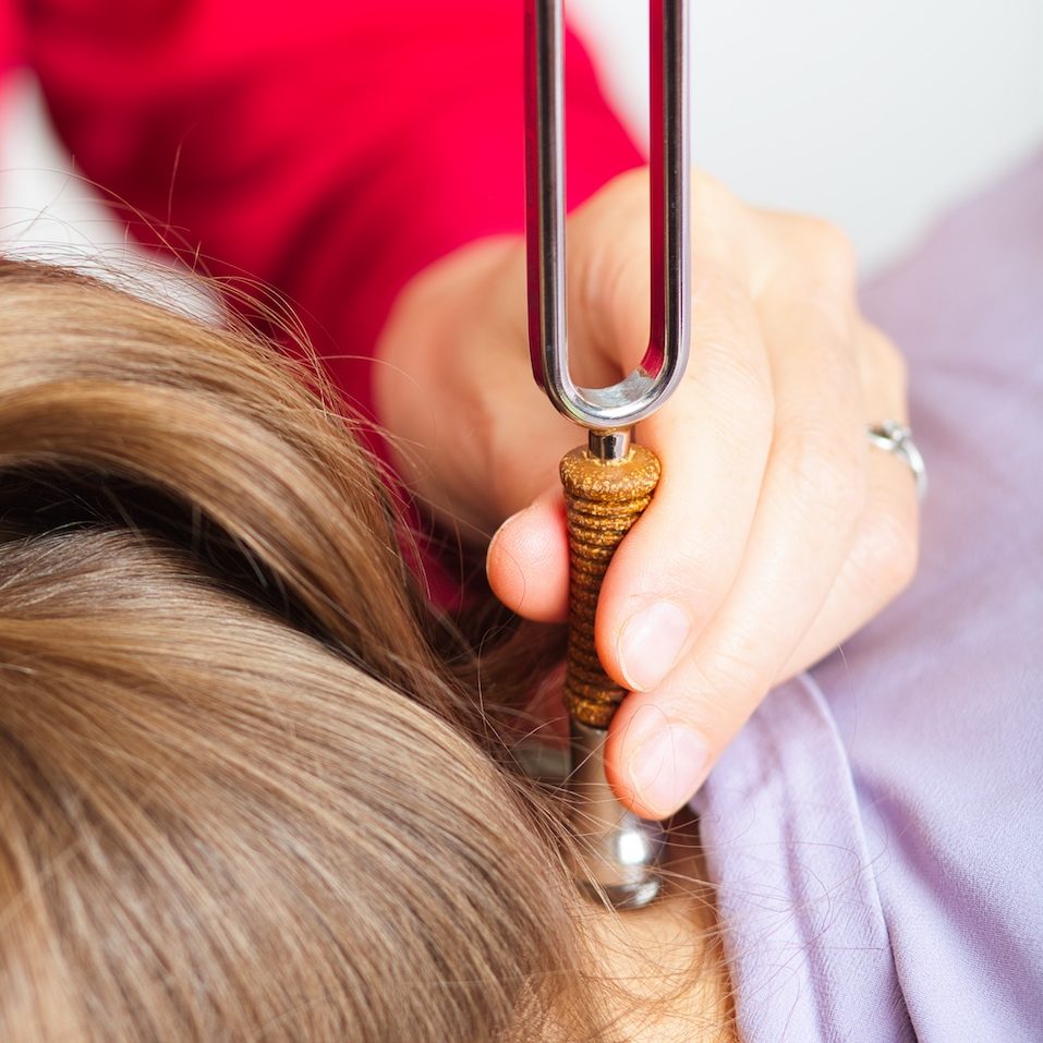 Stimmgabel-Anwendung auf einem Akupunkturpunkt im Nacken