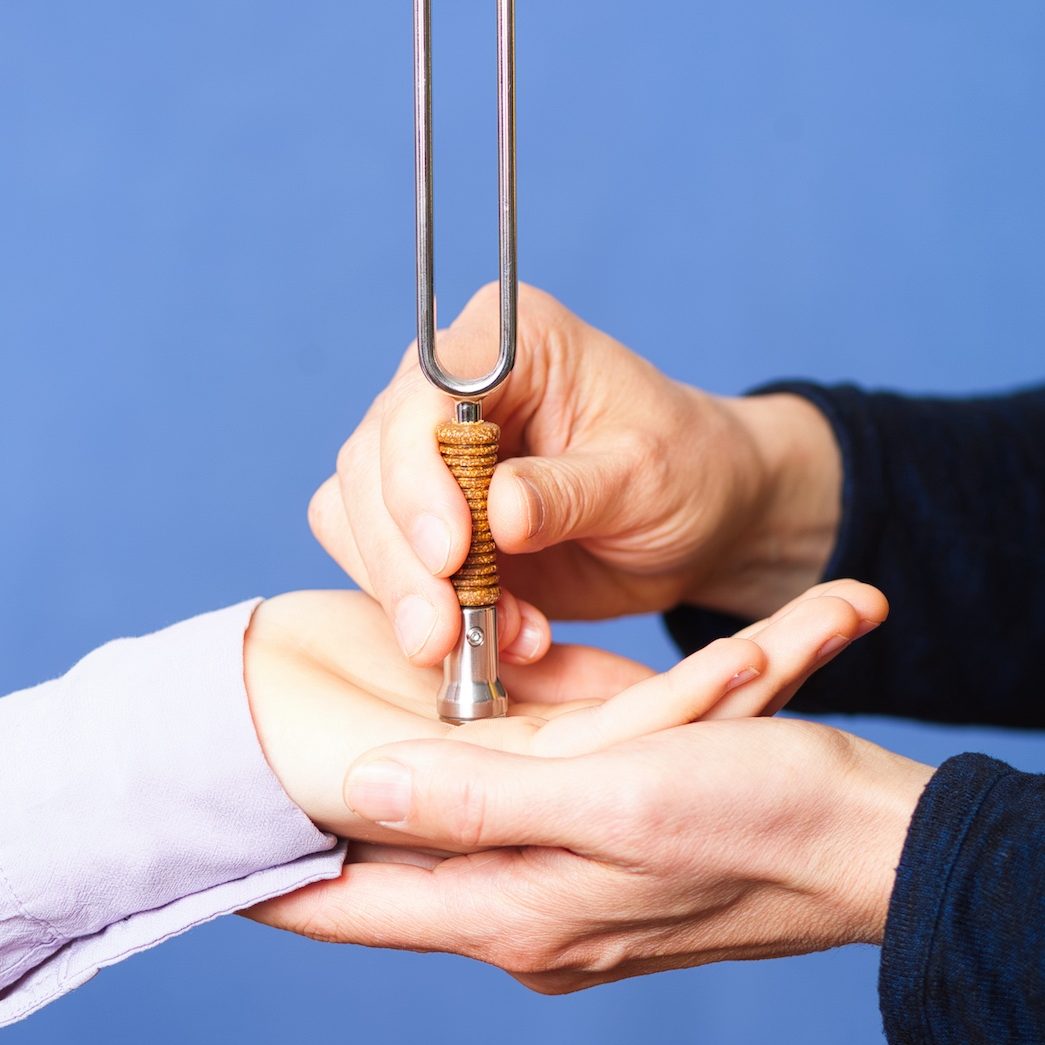 Stimmgabel-Anwendung auf einem Akupunkturpunkt der Handfläche